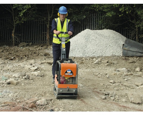 Bauarbeiter verdichtet Boden mit einer Rüttelplatte.