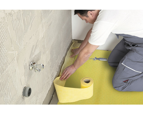 Dural Dichtband DURABASE WP für Wand und Boden Länge 5 m Breite 15 cm Ein Mann verlegt eine gelbe Dichtbahn im Badezimmer an der Wand.
