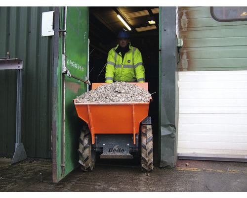 Ein Mann transportiert Schotter mit einem Dumper aus einem Gebäude.