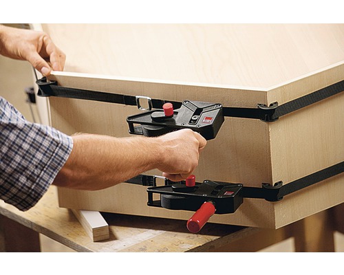Eine Person sichert ein Holzwerkstück mit einer Gurtschelle von Bessey