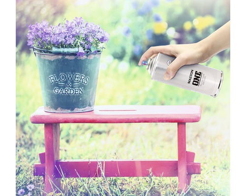 Szene mit Blumen in einem Zinkeimer auf einem Hocker, der mit einer Farbsprühdose besprüht wird.