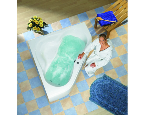 Frau in Bademantel neben gefüllter Eckbadewanne mit Sprudelfunktion in Badezimmer