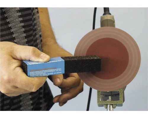 Person hält einen Polierklotz an eine Polierscheibe