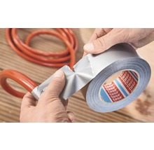 Eine Person repariert einen Schlauch mit Gewebeband. Tesa Logo.