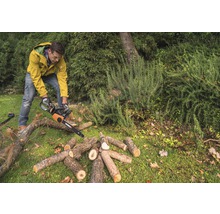 Mann sägt Holz mit einer Kettensäge im Garten.