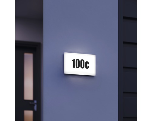Beleuchtetes Hausnummernschild mit der Nummer 100c an einer Wand