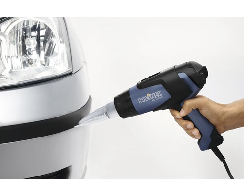 Eine Person verwendet eine Heißluftpistole der Marke Steinel am Stoßfänger eines Autos.