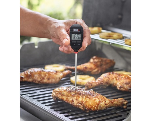 Weber Logo. Person misst mit einem digitalen Grillthermometer die Temperatur von Hähnchen auf einem Grill.