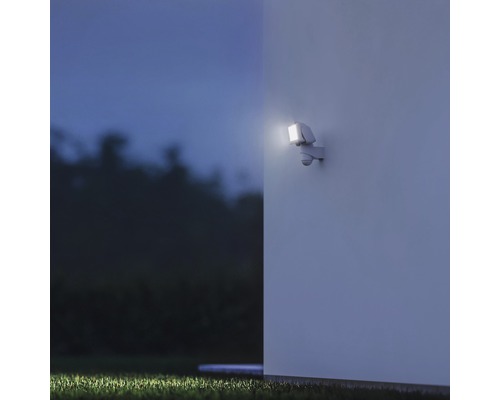 Außenwandleuchte mit Bewegungsmelder beleuchtet eine Hauswand bei Nacht.