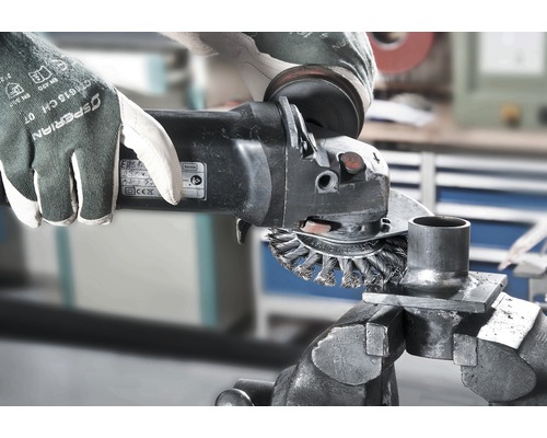Handwerker mit Schutzhandschuhen und Winkelschleifer bei der Metallbearbeitung in einer Werkstatt