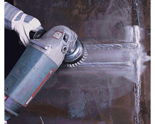 Ein Mann schleift eine Metalloberfläche mit einer Schleifmaschine. Schutzhandschuhe werden getragen.