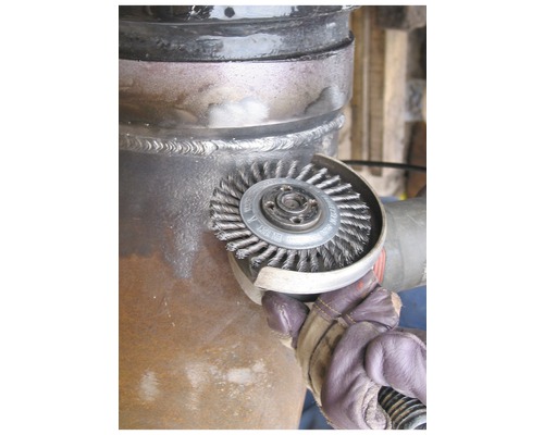 Drahtbürste an einer Rohroberfläche im Einsatz.