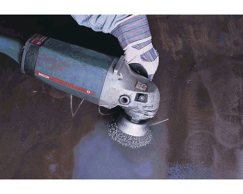 Eine Person benutzt eine Drahtbürste an einer Schleifmaschine.