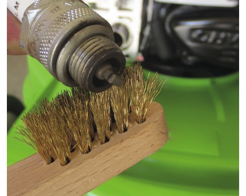 Zündkerze wird mit einer Drahtbürste gereinigt.