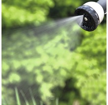 Spritzender Gartenschlauchkopf vor grünem Hintergrund