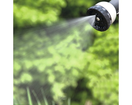 Spritzender Gartenschlauchkopf vor grünem Hintergrund
