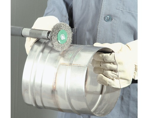 Person mit Handschuhen und Drahtbürste, die ein Metallrohr bearbeitet