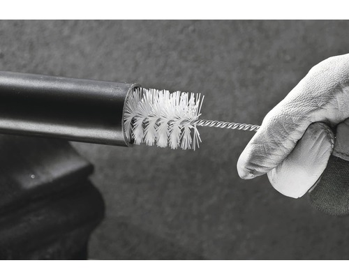 Eine Hand in einem Handschuh reinigt ein Rohr mit einer Rohrbürste.