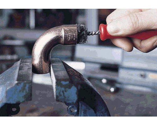 Eine Kupferrohrverschraubung, die in einem Schraubstock befestigt und mit einer Drahtbürste gereinigt wird.