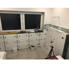 Badezimmer im Bau mit Fliesen an den Wänden, Fenster und Werkzeugen