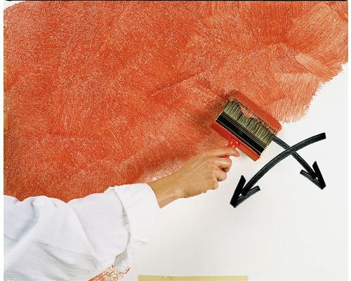 Eine Person streicht eine Wand mit einer großen Bürste, um eine spezielle Maltechnik zu erzielen.