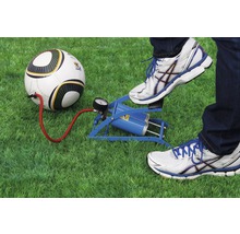Eine Person pumpt mit einer Fußluftpumpe einen Fußball auf Rasen auf.