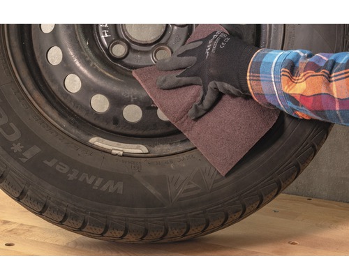 Eine Person schleift einen Reifen mit Schleifpapier.