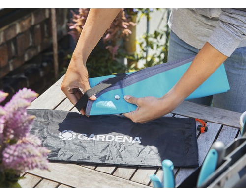 Eine Person verpackt eine Gartengeräte-Kniebank-Auflage von Gardena in einer Tasche.