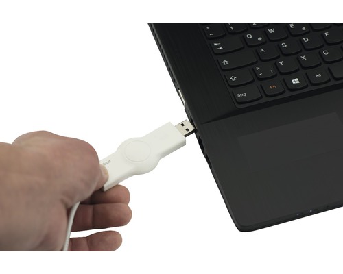 Ein Mann steckt einen weißen USB Stick in einen Laptop.