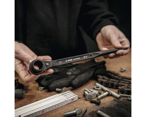 Eine Person hält einen Ringratschenschlüssel der Marke WGB über einem Arbeitstisch mit Werkzeugen.