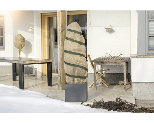 Terrasse mit Pflanzenschutzsäcken und Gartentischen im Winter.