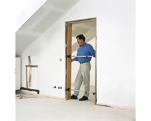 Mann montiert Türzarge mit Spreizen in einem Raum mit Dachschräge.