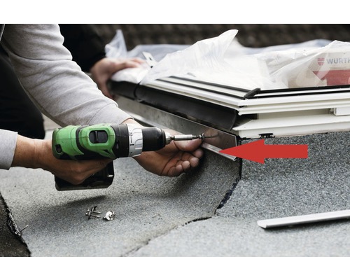 Handwerker befestigt Dämmung mit einem Akku-Schrauber an einem Dachfenster.