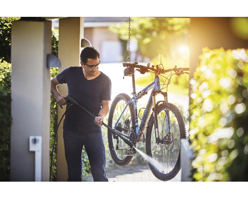 Mann reinigt Fahrrad mit Hochdruckreiniger