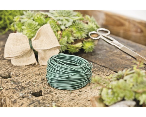 Floristikdraht, Schere, Schleife und Pflanzen auf einem Tisch