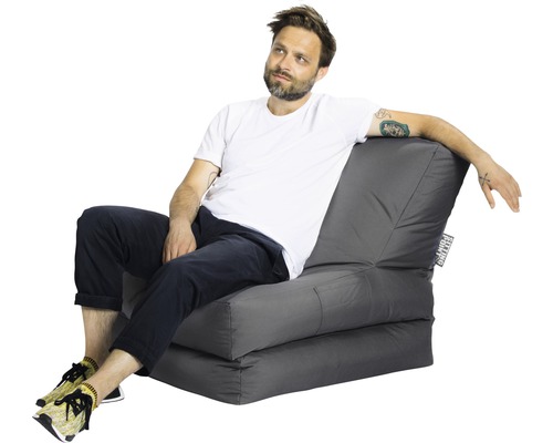 Mann sitzt auf einem grauen Schlafsessel