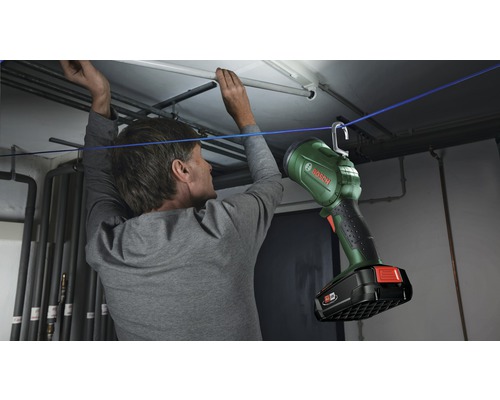 Mann befestigt Bosch Arbeitsleuchte mit Haken an einer Schnur in einem Kellerraum
