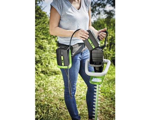 Frau wechselt Akku an Heckenschere mit Akku-Gürtel
