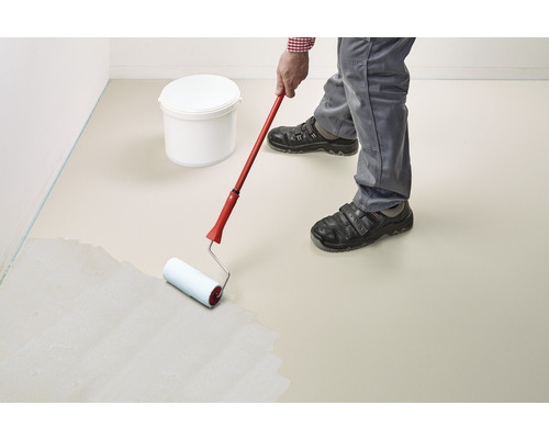 Eine Person streicht einen Boden mit einer Farbwalze. Im Hintergrund steht ein Farbeimer.