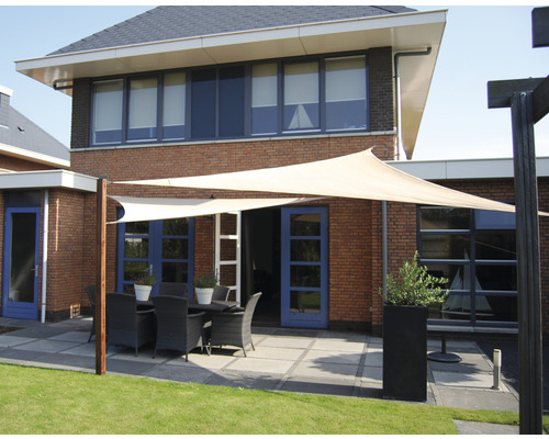 Terrasse mit Sonnensegel, Gartentisch und Stühlen vor einem Backsteinhaus