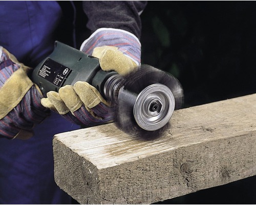 Eine Drahtbürste im Einsatz auf einem Holzbrett.