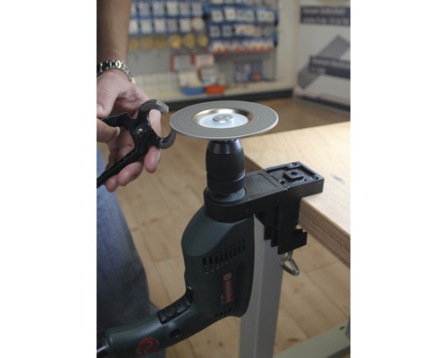 Person schärft Zange mit Schleifscheibe auf Bohrmaschine