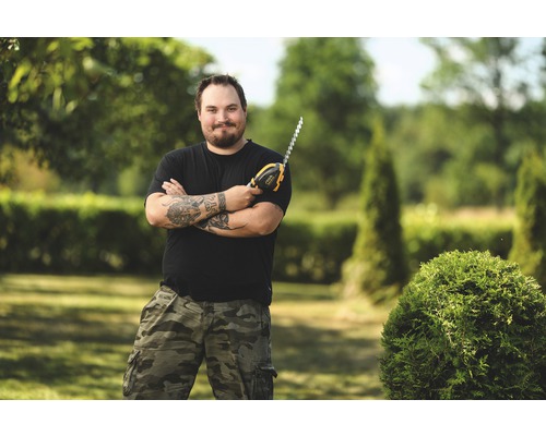 Mann mit Akku-Heckenschere im Garten