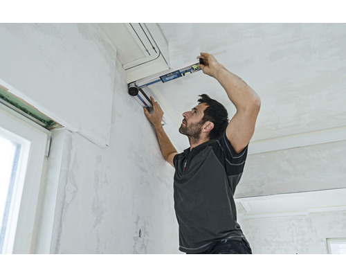 Ein Mann benutzt eine Wasserwaage zur Ausrichtung in einem Raum.