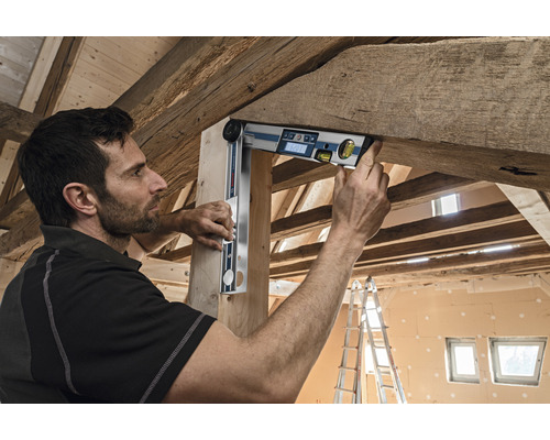 Handwerker verwendet eine digitale Winkelwasserwaage an einem Holzbalken