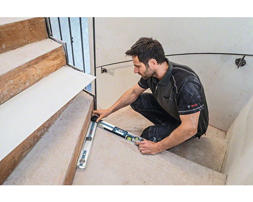 Handwerker misst Treppe mit Winkelmesser