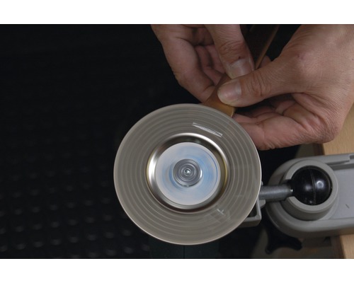 Person schleift Metall mit einer Schleifscheibe