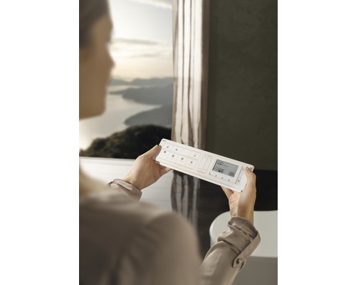 Frau hält ein Hausautomationssystem in einem Badezimmer.