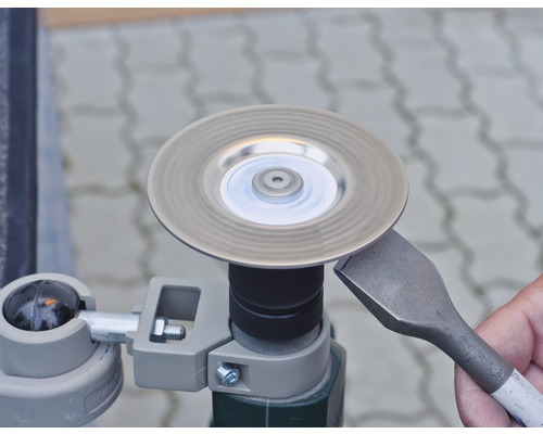 Eine Stechbeitel wird an einer Schleifscheibe geschärft.