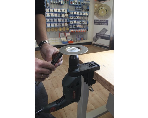 Eine Person schärft einen Bohrer mit einer Bohrmaschine und einer Schleifscheibe.